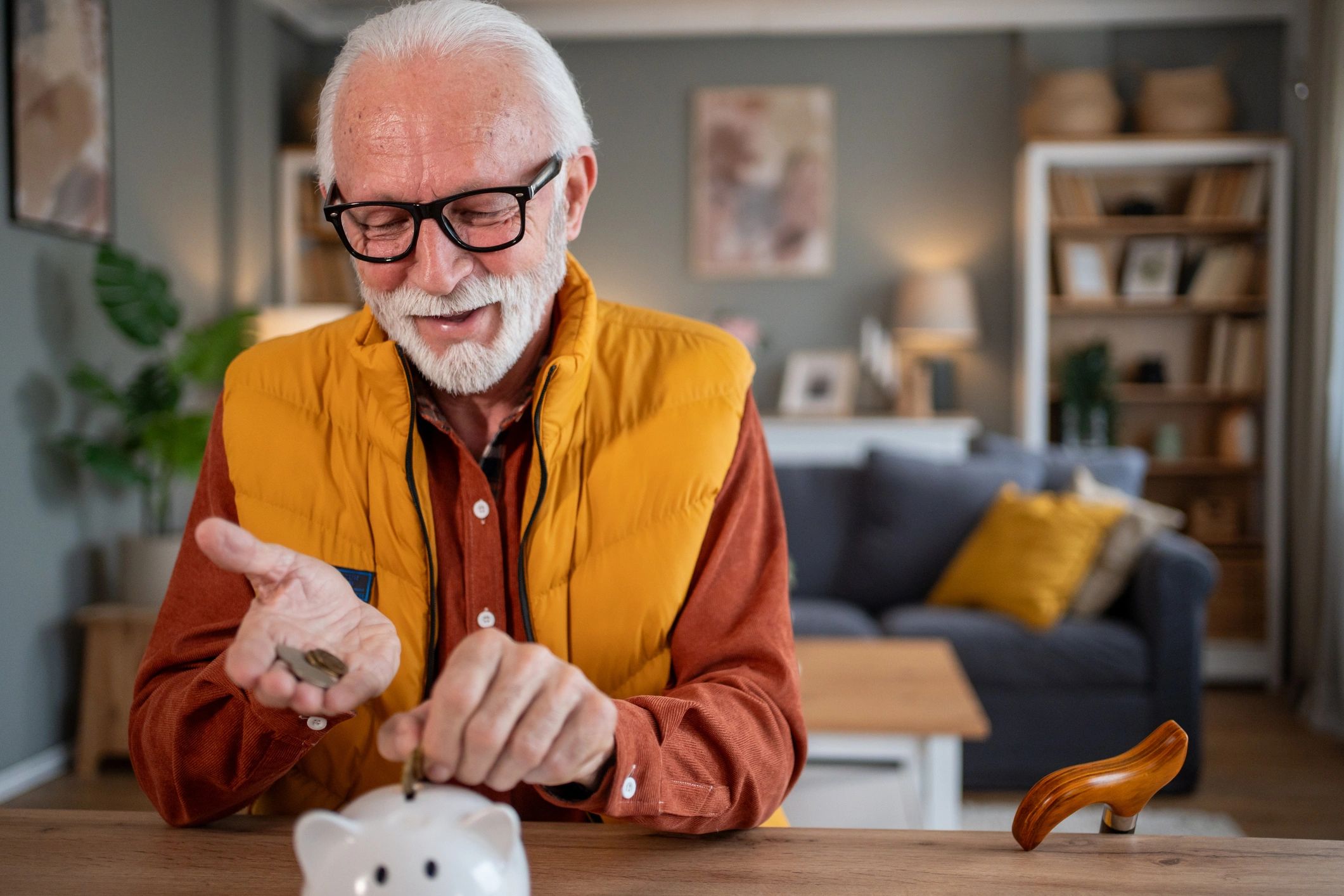 Happy senior man saving money in piggy bank at home